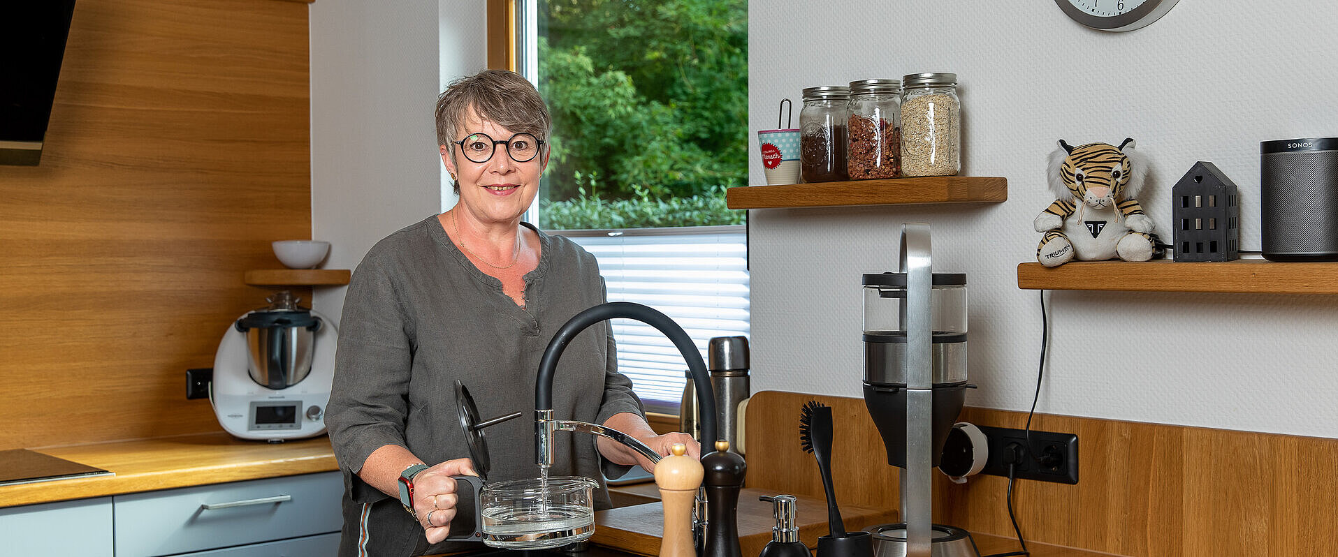 Frau steht in der Küche am Wasserhahn