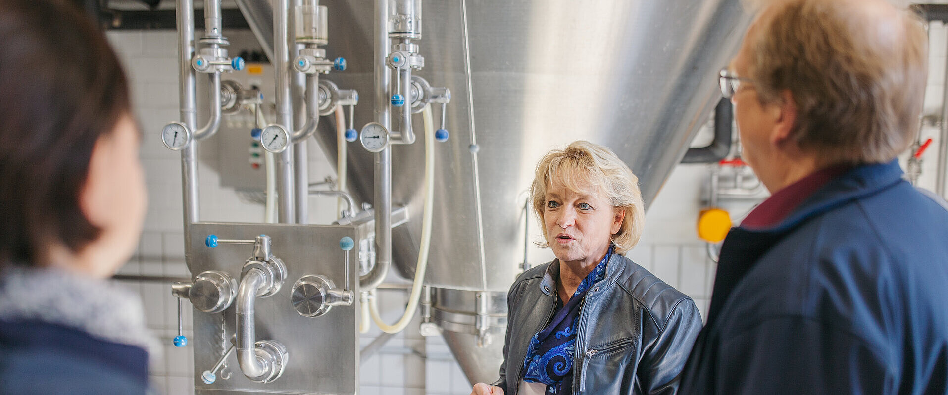 Drei Personen im Gespräch in einer Brauerei.