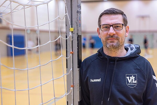 Portraitfoto Mihael Dümeland neben einem Handballtor.