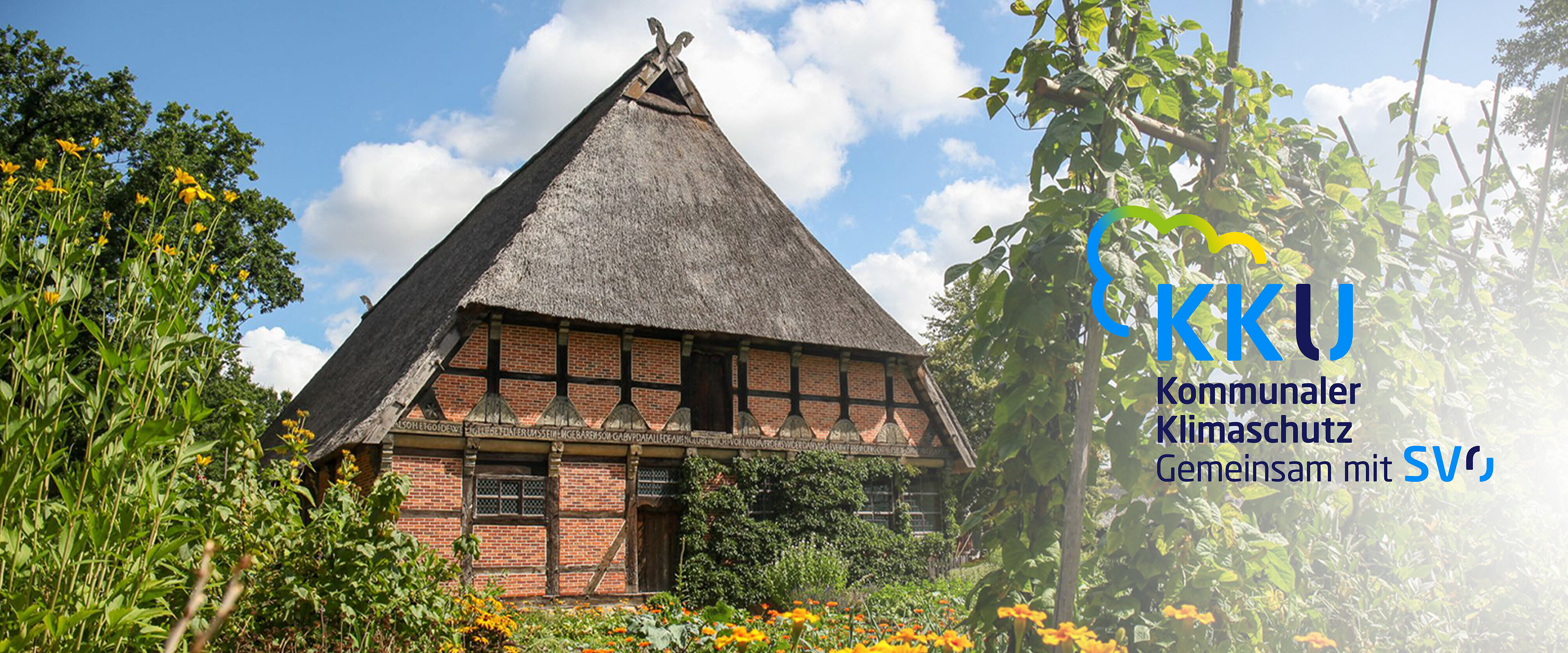 Reetdachhhaus, von Bäumen umgeben.