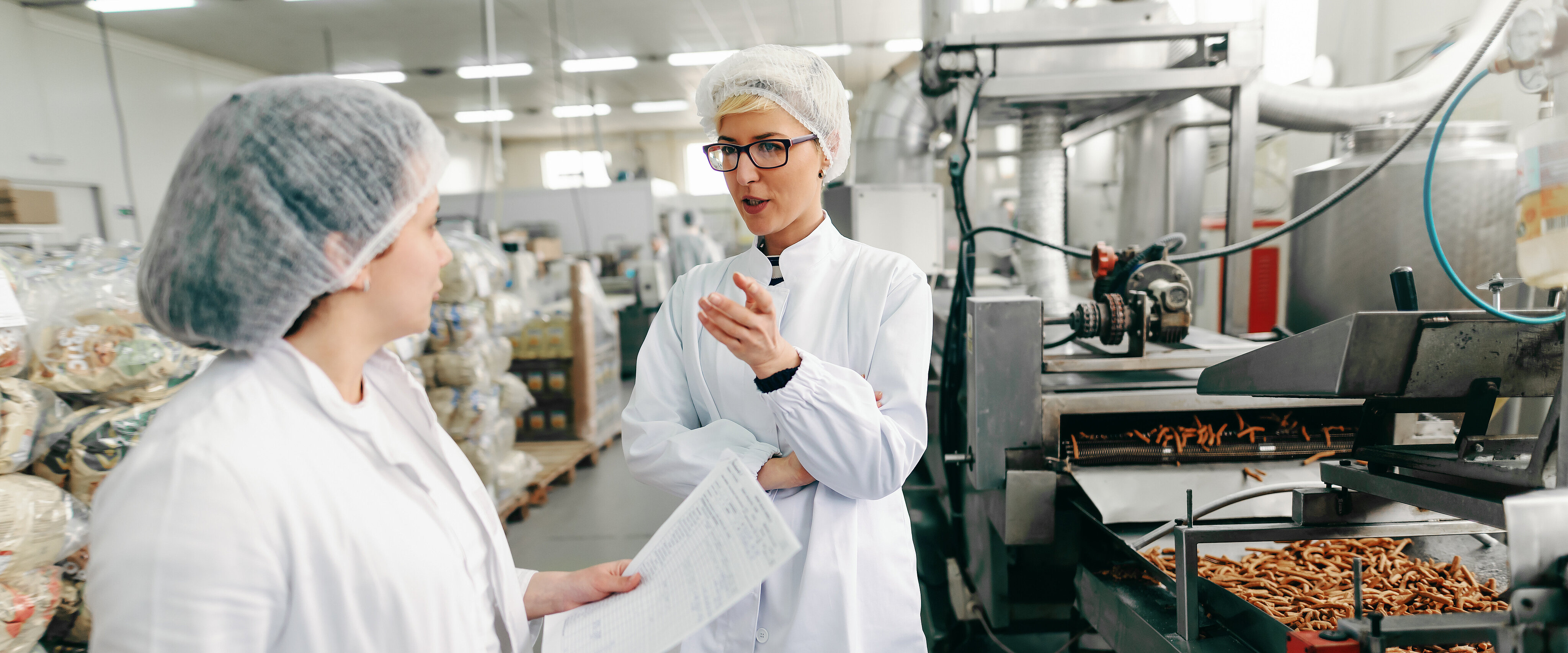 Zwei Mitarbeiter in der Lebensmittelproduktion diskutieren über Qualitätskontrolle.