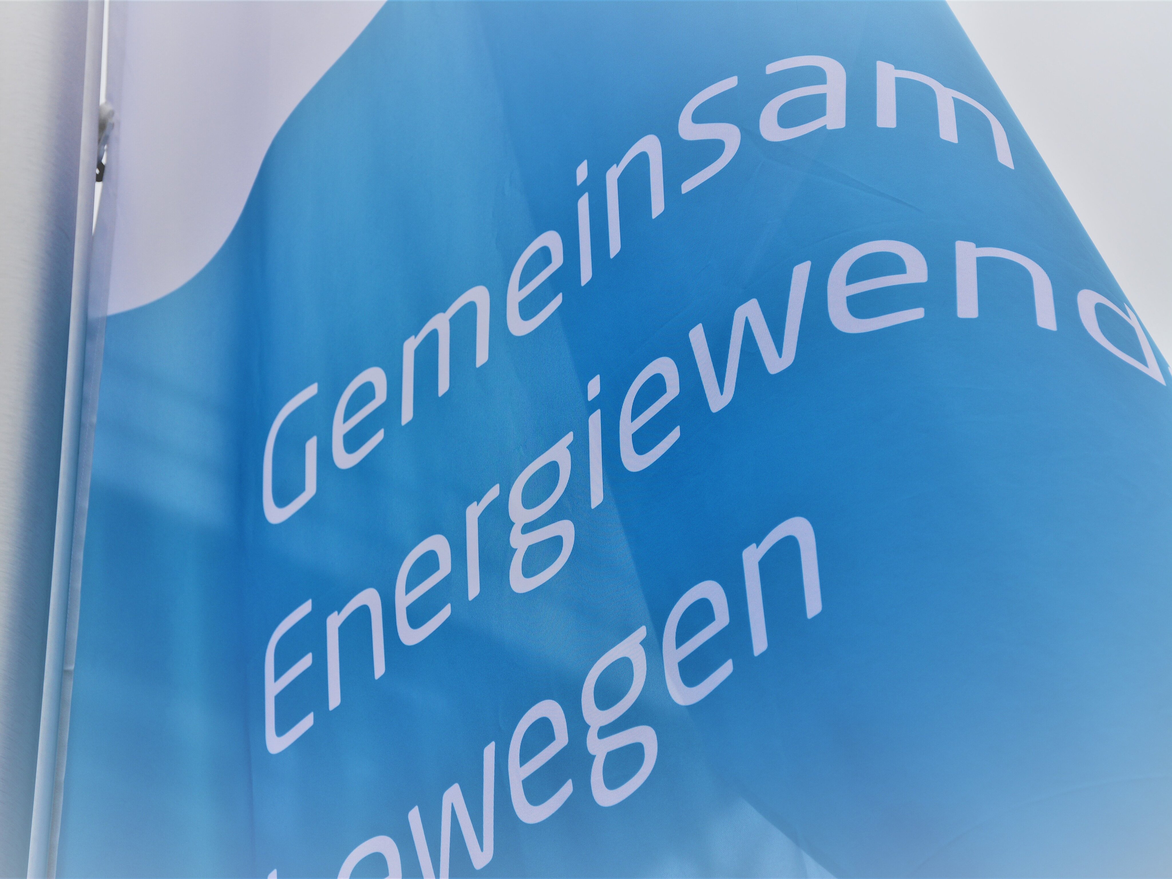 Eine Fahne weht im Wind. Auf ihr steht: Gemeinsam Eneriewende bewegen.