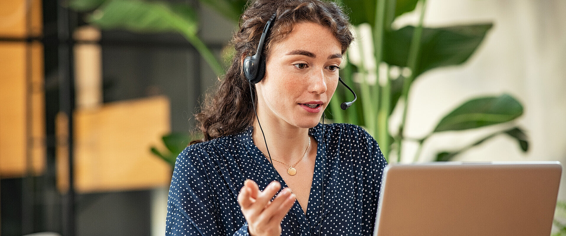 Kundenservice mit einer Mitarbeiterin am Arbeitsplatz und mit Headset.